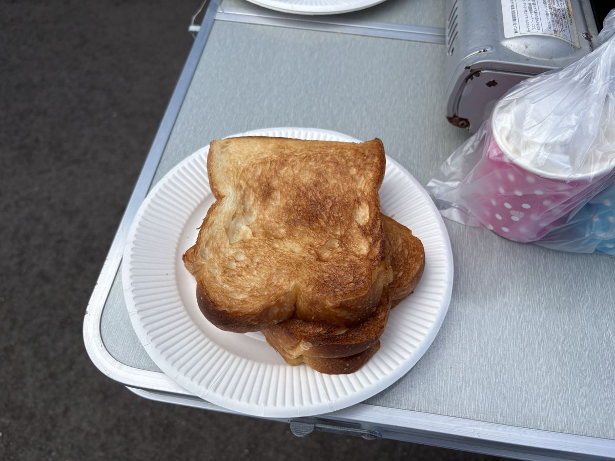 紙皿にのった焼きたてのトースト2枚。屋外の折りたたみテーブルの上に置かれている