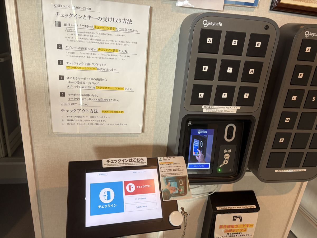 集合棟BASEのセルフチェックイン。タブレットと、A〜Nの棟ごとに分かれたキーボックスが並ぶ