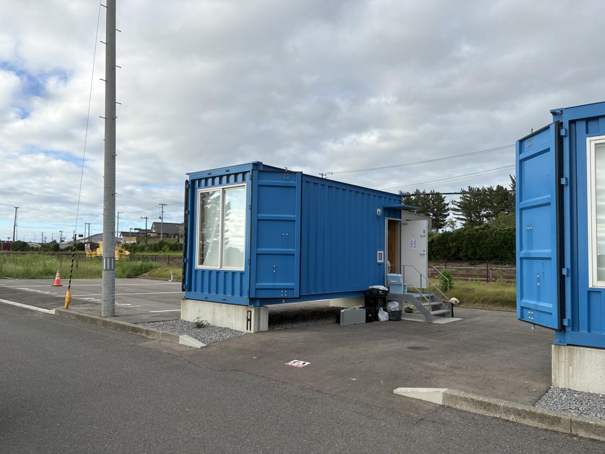 SAKATANTO Container Hotel CAMPSのコンテナ客室。青い20フィートコンテナが並び、各棟の前が駐車スペースになっている