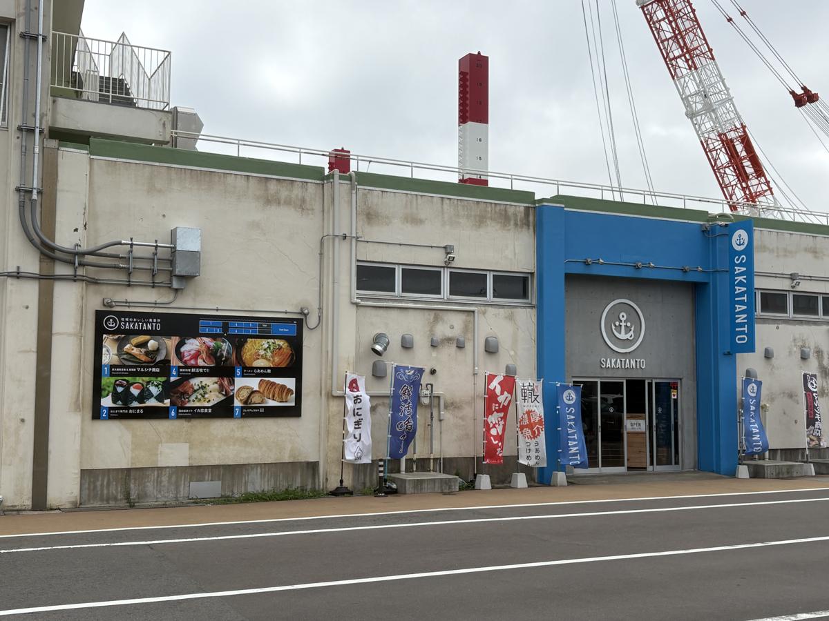 SAKATANTOの外観。青い入口と店名の看板、のぼり旗が並ぶ