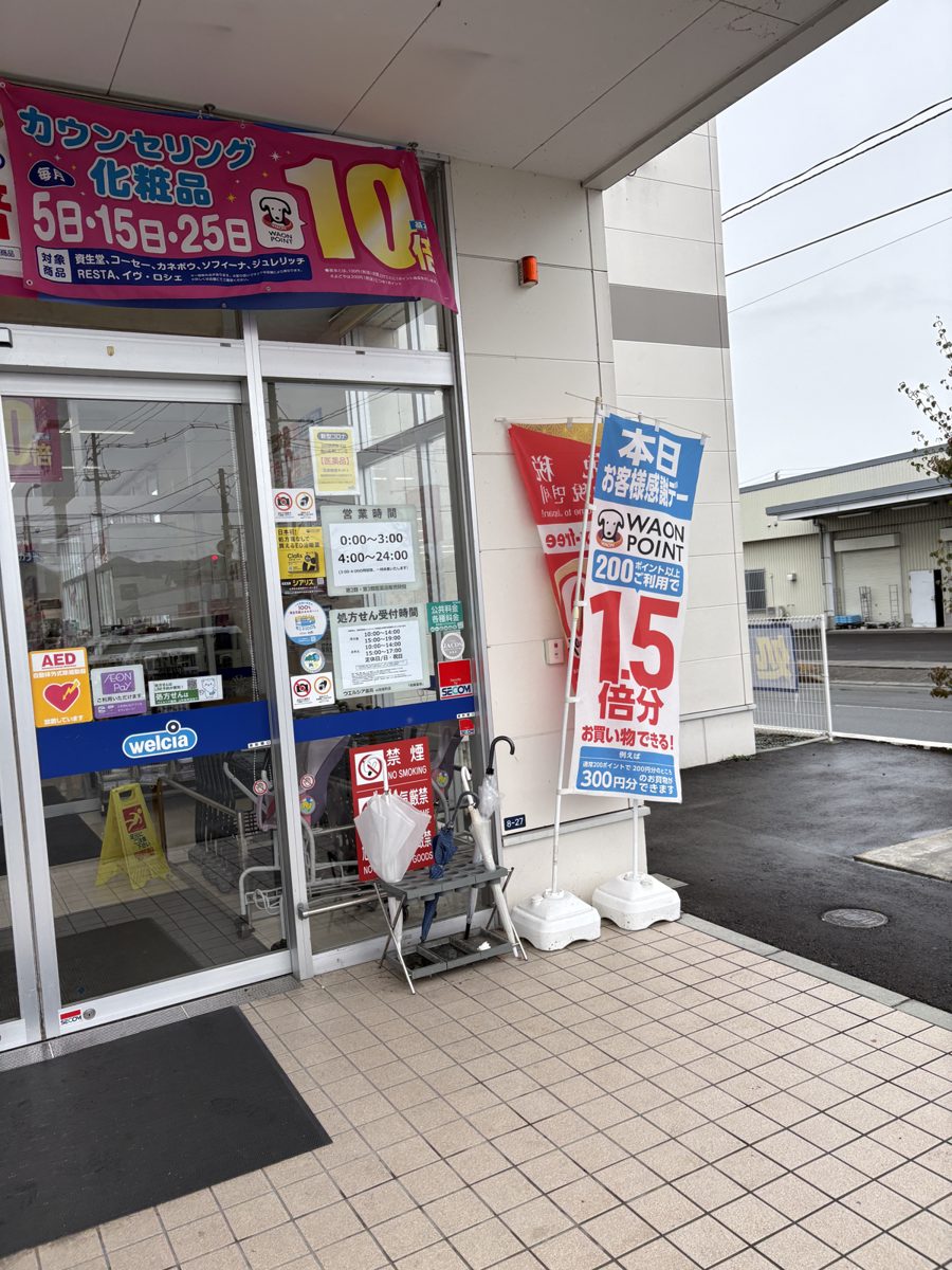ウエルシア山形桧町店の入口に立つお客様感謝デーののぼりと営業時間の掲示