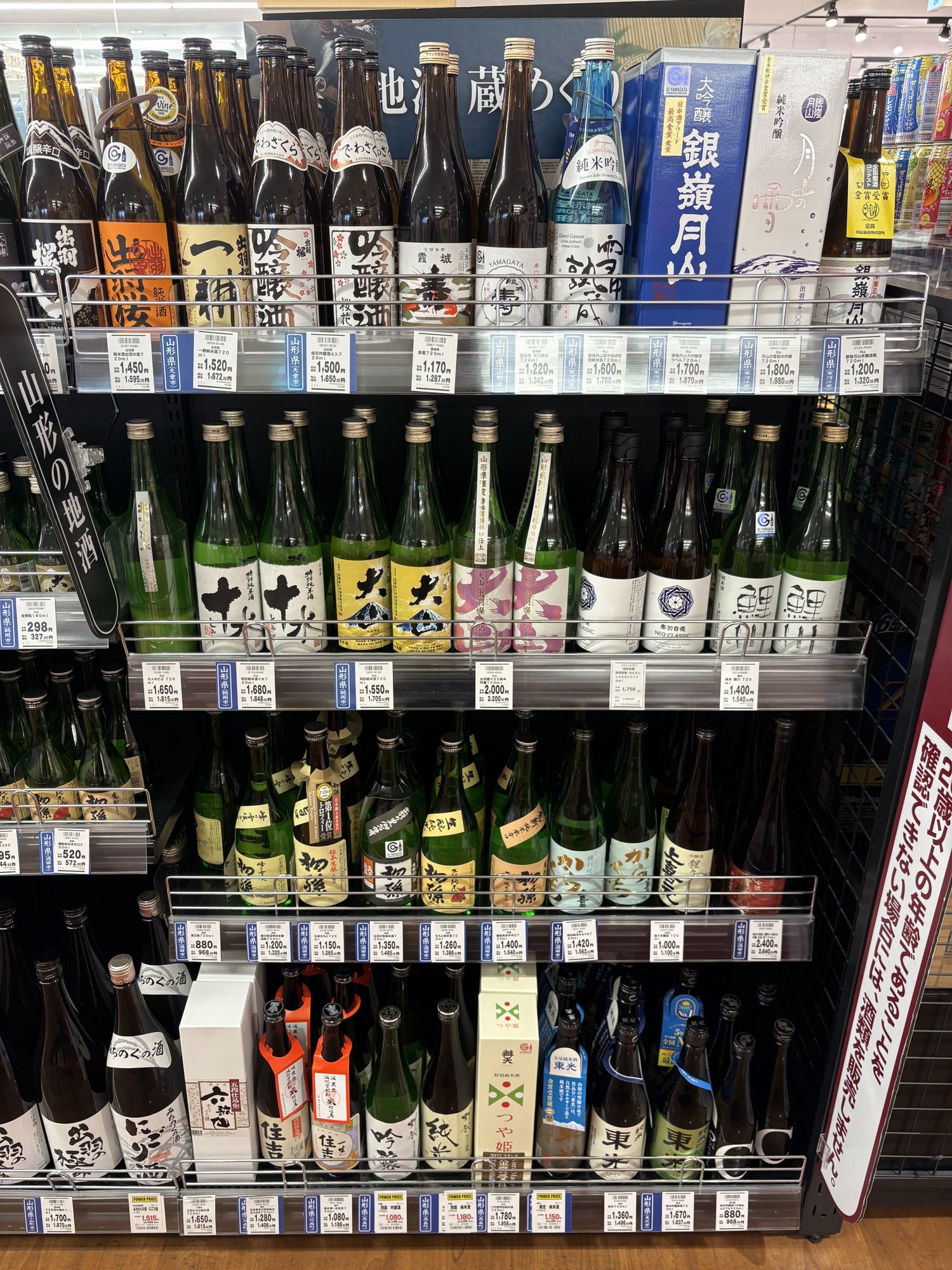 ヤマザワ北町店の「山形の地酒」の棚。出羽桜・初孫・大山・鯉川・東光の瓶と値札